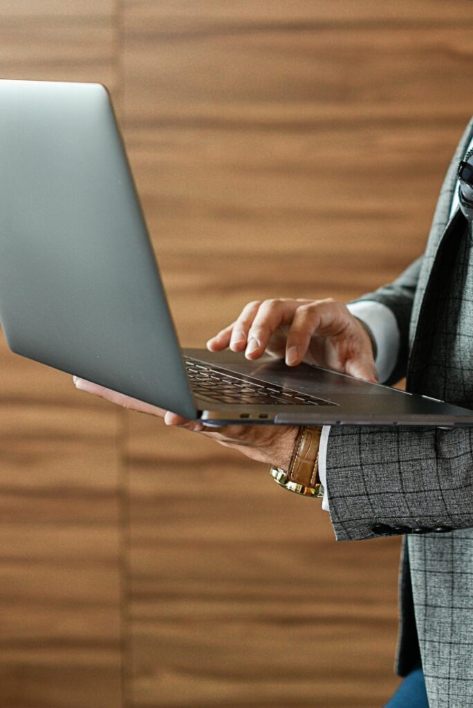 Close-up of a businessman using a laptop indoors, focused on the typing action.